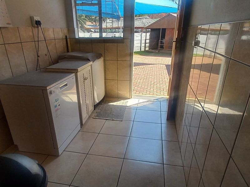 A functional laundry room featuring tiled walls and flooring, with direct access to the outdoor area.