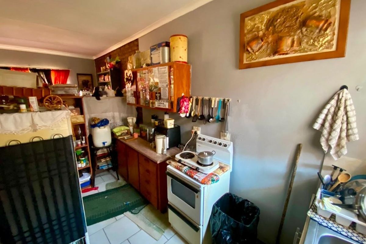 A compact kitchen area featuring built-in cabinetry, a freestanding stove, and tiled flooring, offering potential for modernization and improved layout efficiency.