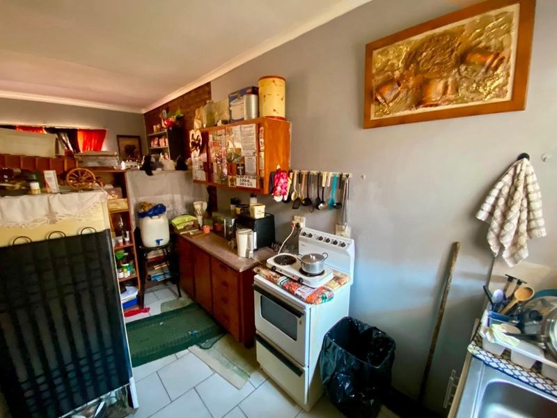 A compact kitchen area featuring built-in cabinetry, a freestanding stove, and tiled flooring, offering potential for modernization and improved layout efficiency.
