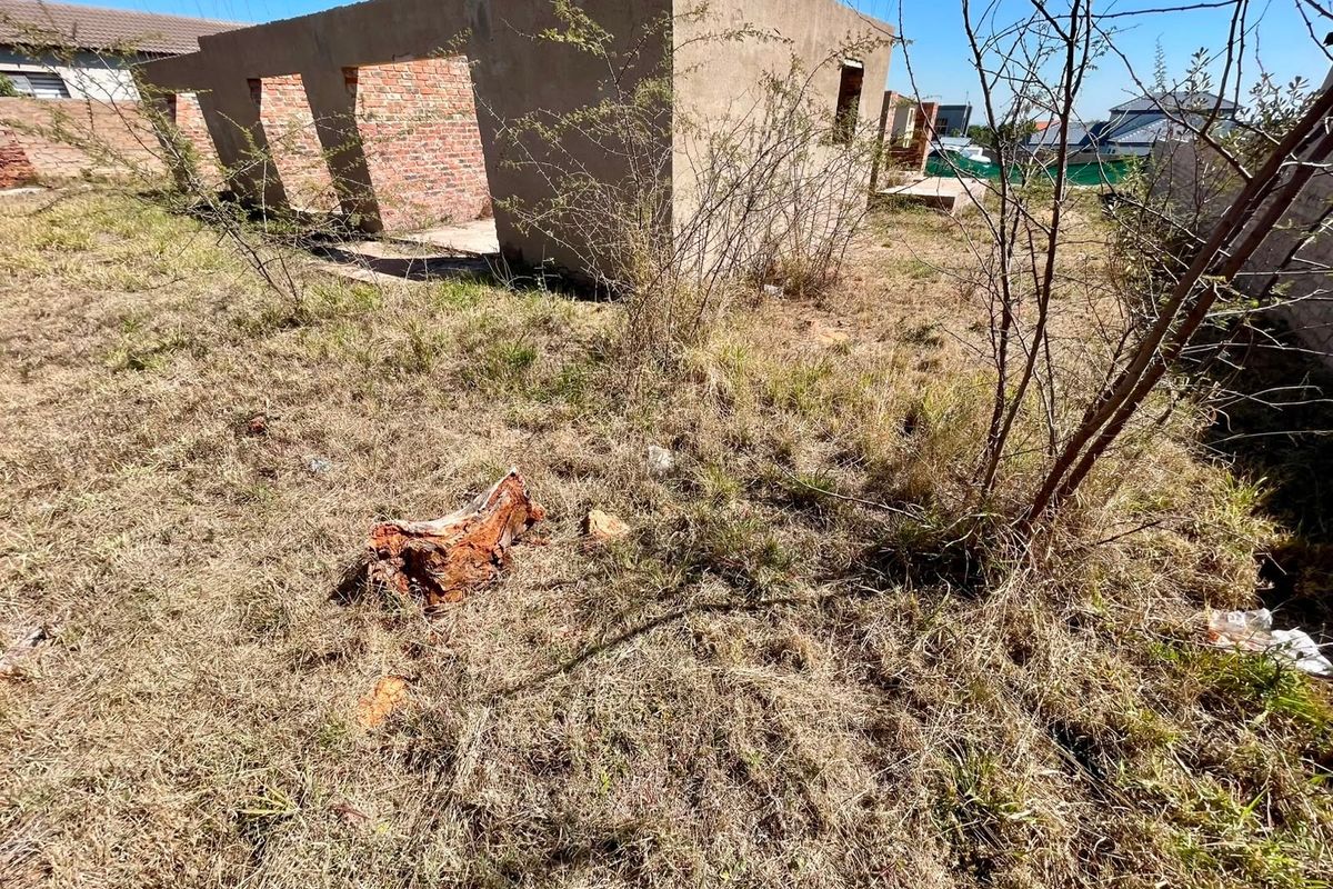 A view of an unfinished residential brick structure on a vacant plot, requiring completion and site clearing.