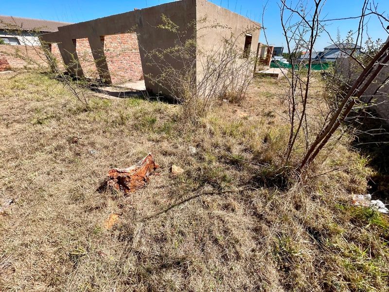 A view of an unfinished residential brick structure on a vacant plot, requiring completion and site clearing.