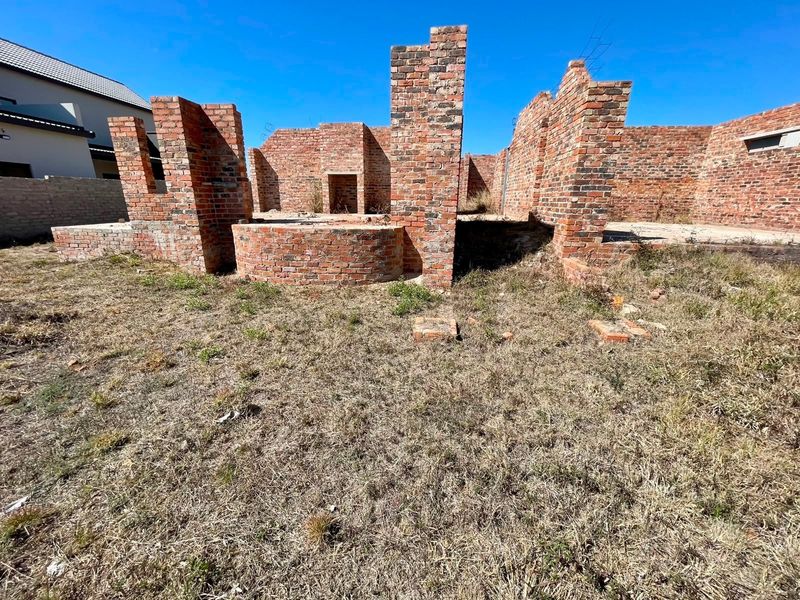 A residential property under construction featuring exposed brick walls and foundation, representing a shell-stage development on a vacant plot.