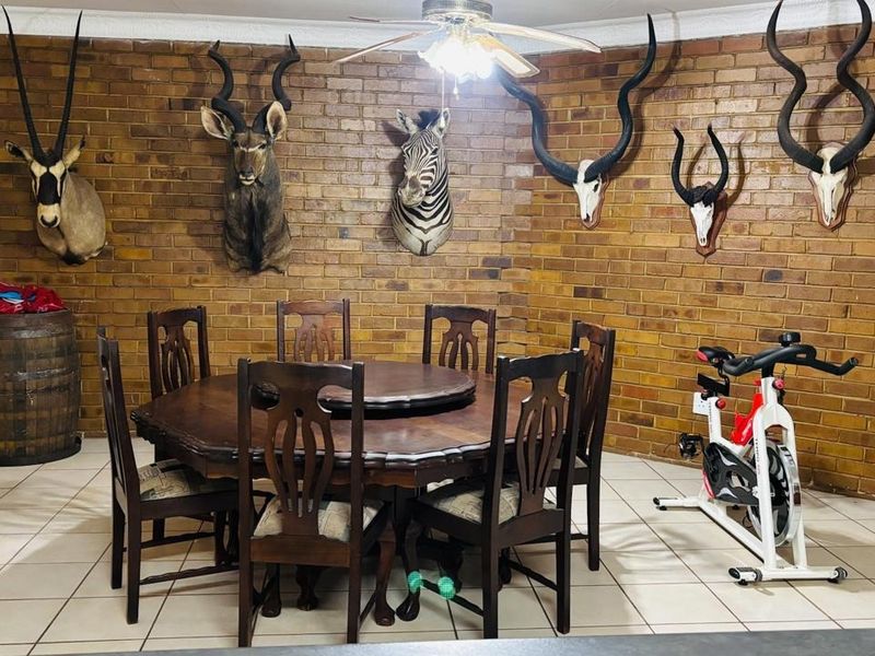 Dining room featuring an exposed brick feature wall, tiled flooring, and a ceiling fan.