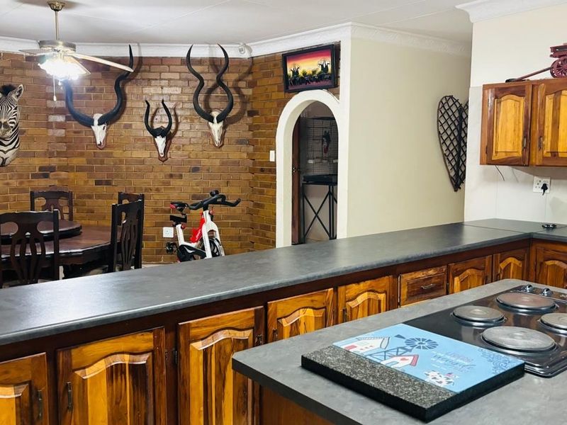 Open plan kitchen and dining area featuring exposed brick walls, traditional wooden cabinetry, and a functional electric hob setup.