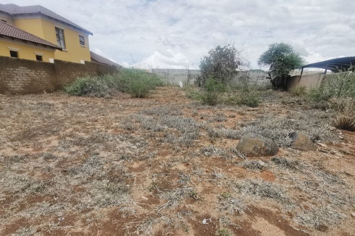 A vacant residential plot featuring natural ground cover and perimeter boundary walls, offering a blank canvas for future development.