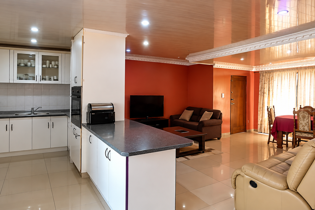 Open-plan living area featuring a functional kitchen with built-in cabinetry, tiled flooring, and a seamless flow into the dining and lounge spaces.
