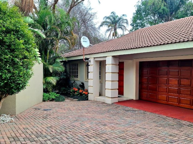 Front exterior view of the townhouse featuring a brick paved driveway, covered entrance, and a wooden garage door.