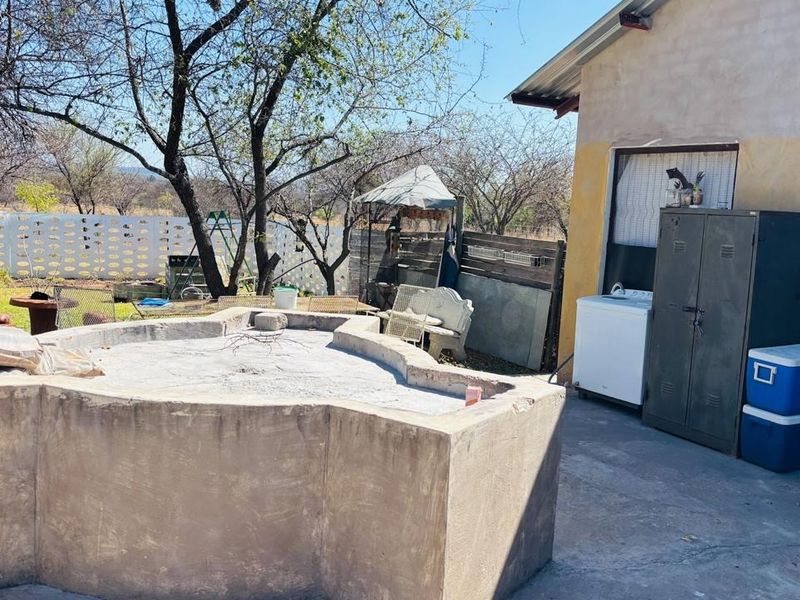 Rear exterior area featuring a concrete pool structure, paved patio space, and perimeter walling on a farm property.