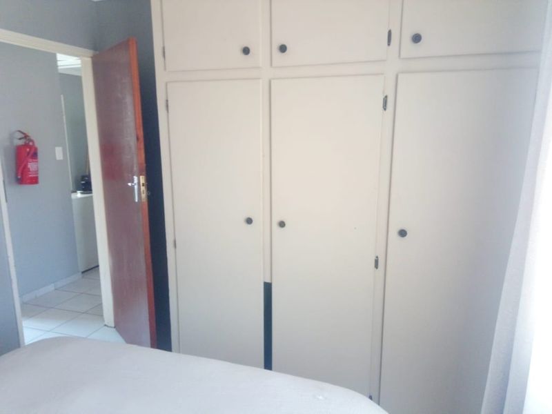 A bedroom featuring built-in cupboards with a view into an adjacent hallway area.