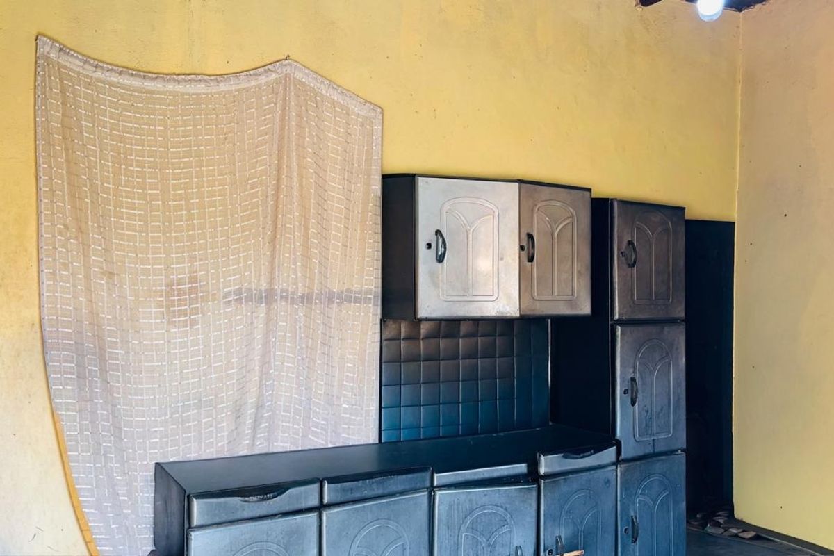 A basic kitchen area featuring built-in cabinetry and a tiled splashback, requiring cosmetic updates and refurbishment to improve its overall condition and appeal.