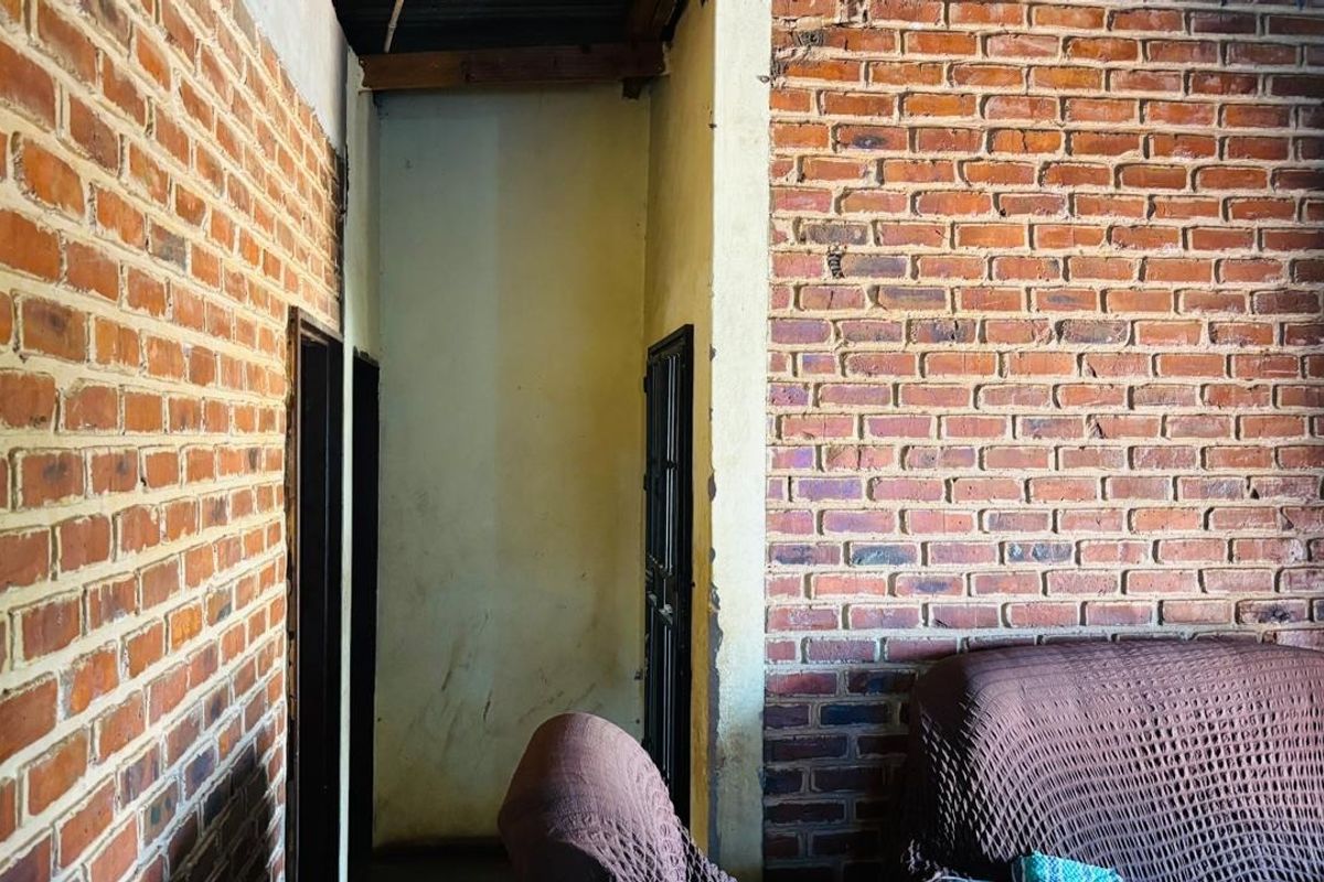Living area featuring exposed brick walls and industrial-style finishes, requiring cosmetic updates and plasterwork repairs to improve the overall aesthetic.