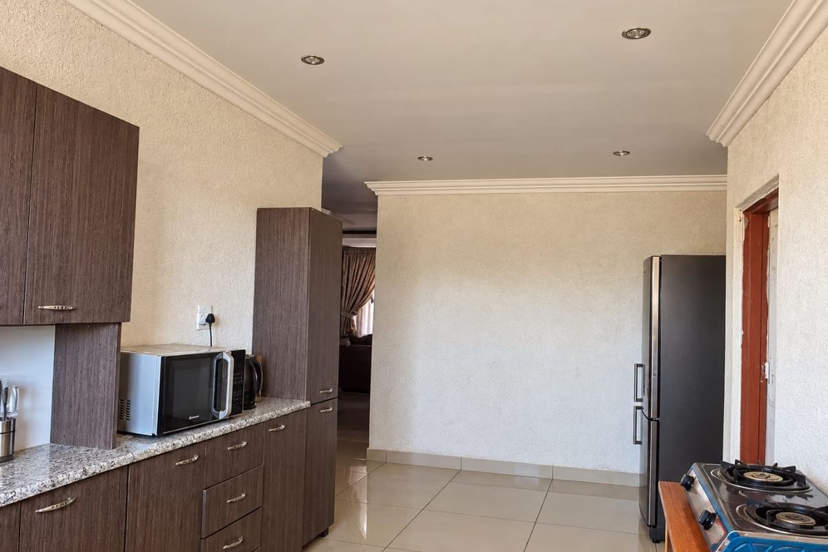 A functional kitchen featuring dark wood cabinetry, granite countertops, tiled flooring, and recessed ceiling lighting, providing a clean and practical workspace.