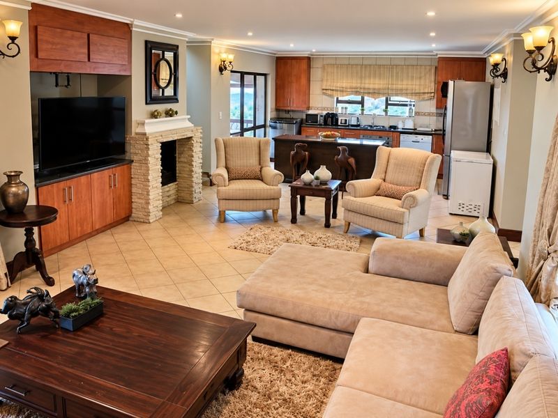 Spacious open-plan living area featuring a stone-clad fireplace, tiled flooring, and a functional kitchen with island and built-in cabinetry.