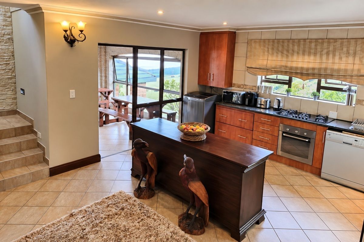 A well-appointed kitchen featuring warm wood cabinetry, a central island, built-in appliances, and a striking stone-clad feature wall leading to an adjacent patio area.