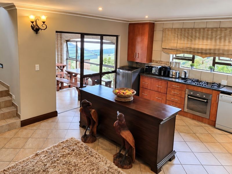A well-appointed kitchen featuring warm wood cabinetry, a central island, built-in appliances, and a striking stone-clad feature wall leading to an adjacent patio area.