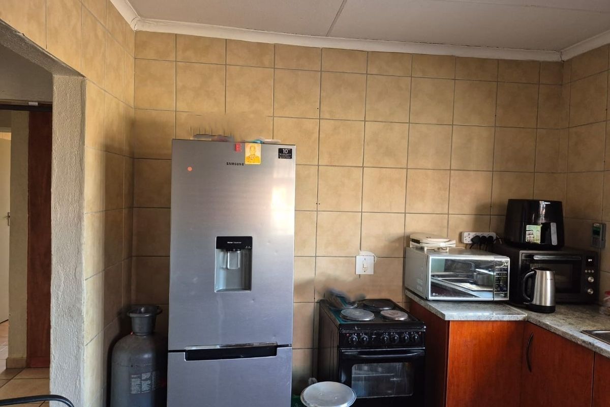 A functional kitchen featuring tiled walls, built-in cabinetry, and a freestanding electric stove, offering potential for modernization and aesthetic updates.