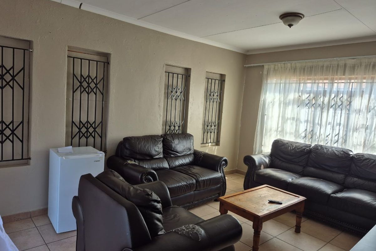 A living room featuring tiled flooring, security gates on windows, and neutral wall tones, offering a functional space ready for cosmetic updates.