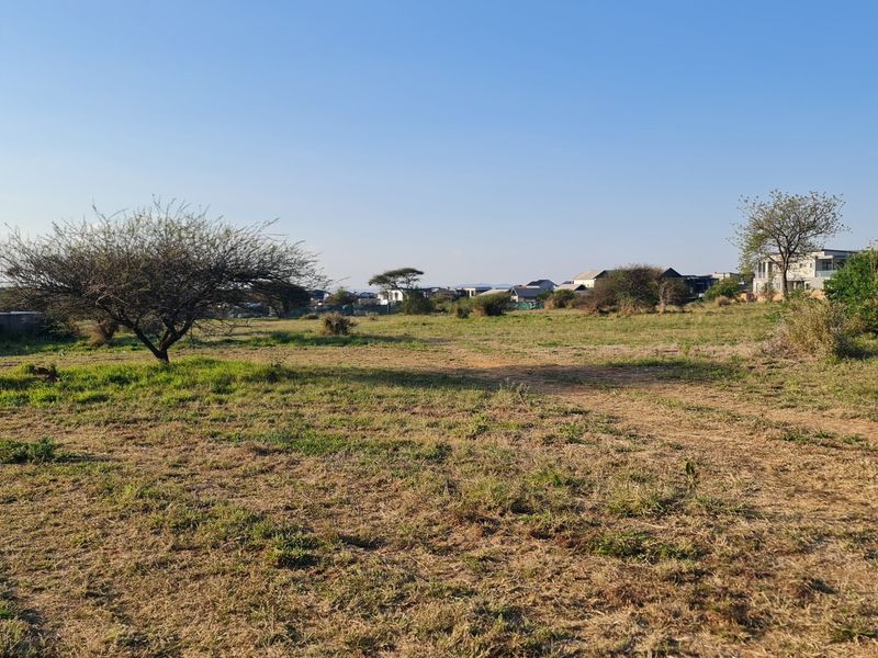 A view of a vacant residential plot featuring natural grass and scattered trees, suitable for future development.