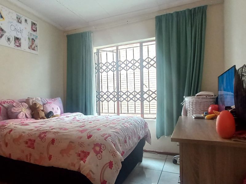 A functional bedroom featuring tiled flooring and a window fitted with a security gate.