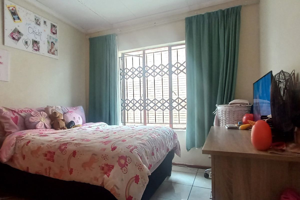 A functional bedroom featuring tiled flooring and a window fitted with a security gate.