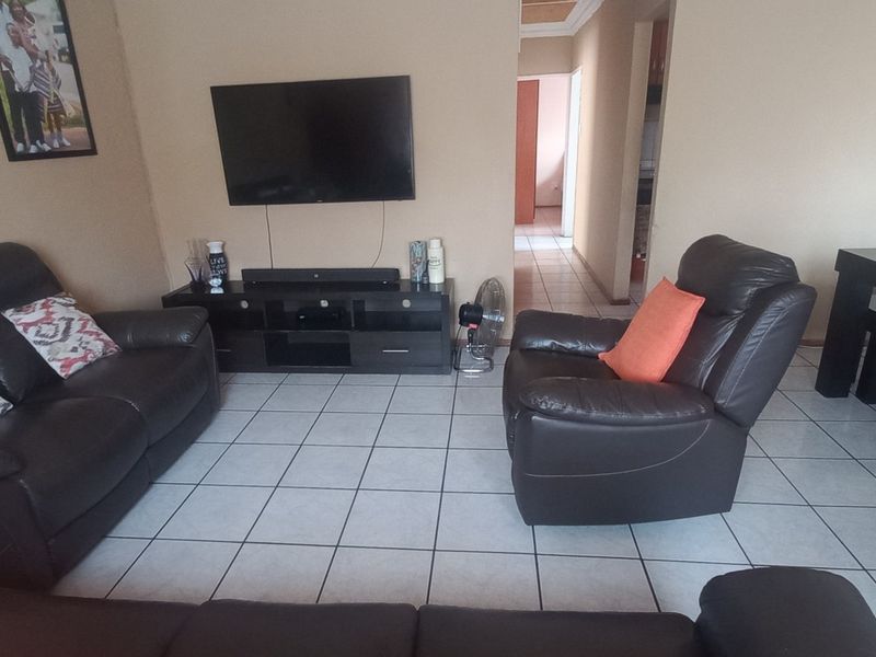 A spacious living room featuring neutral wall tones and tiled flooring, providing a functional and open layout for comfortable family living.