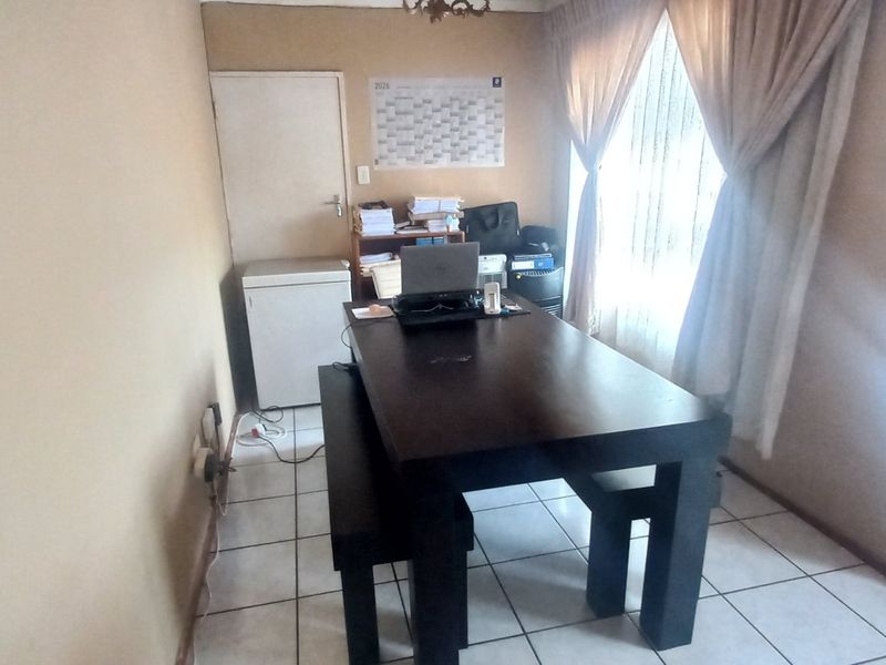 A functional dining area featuring tiled flooring and a security gate, providing a practical space for meals or home office use.