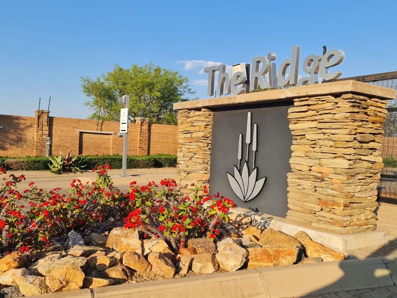 Entrance signage and security perimeter wall for The Ridge residential estate, featuring stone cladding and electric fencing.