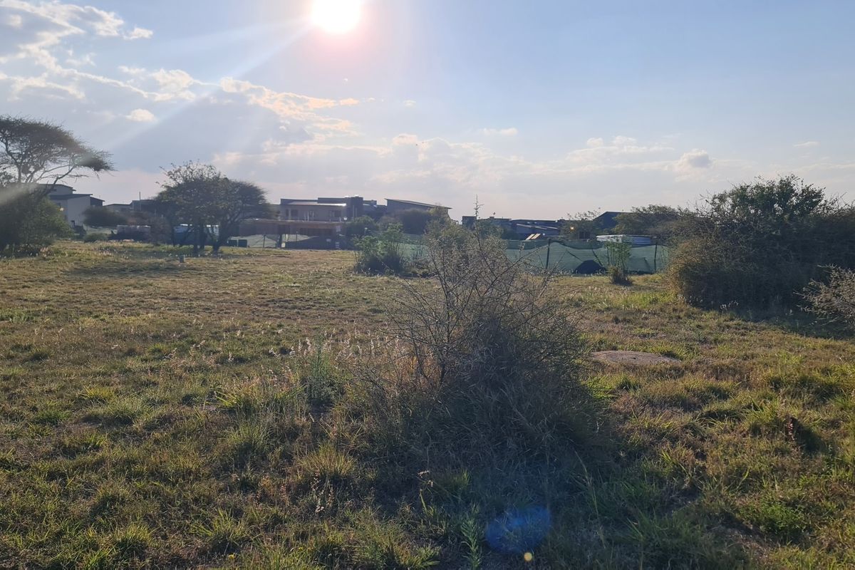 A view of a vacant residential plot featuring natural grass and scattered vegetation, suitable for future development.