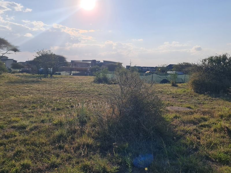 A view of a vacant residential plot featuring natural grass and scattered vegetation, suitable for future development.