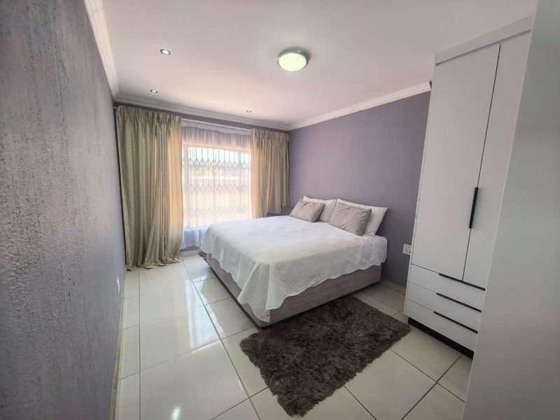 A well-maintained bedroom featuring tiled flooring, recessed downlighting, and a built-in wardrobe, offering a clean and functional living space.