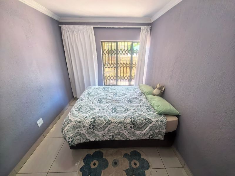 A standard bedroom featuring tiled flooring, security gate on the window, and crown molding, providing a functional space with potential for cosmetic updates.