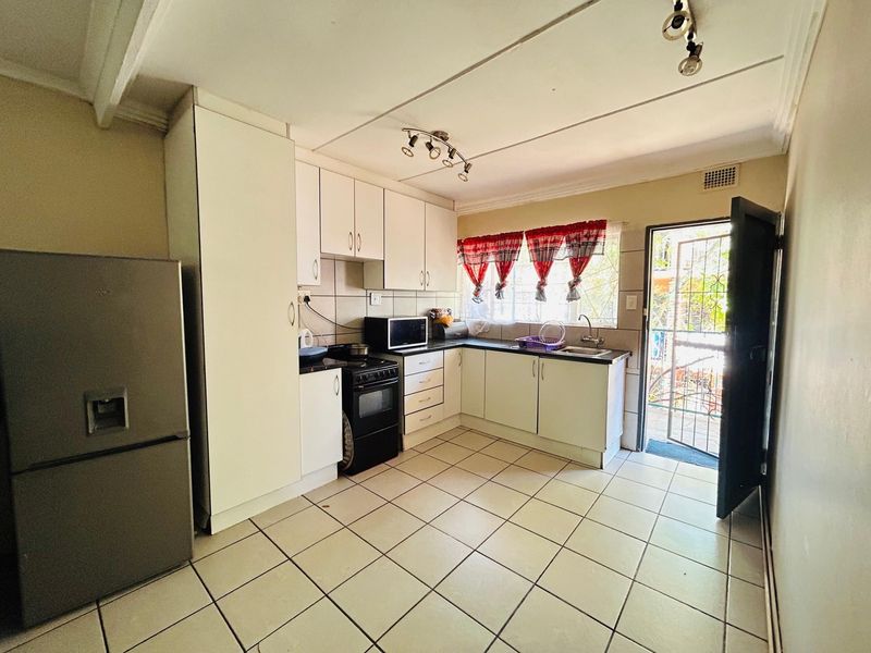 Functional kitchen featuring white cabinetry, tiled flooring, and direct access to an outdoor area through a security gate.