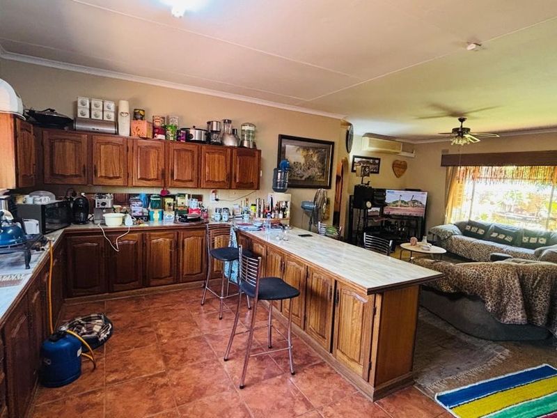 Open-plan kitchen and living area featuring wooden cabinetry, a breakfast bar, tiled flooring, and integrated air conditioning.
