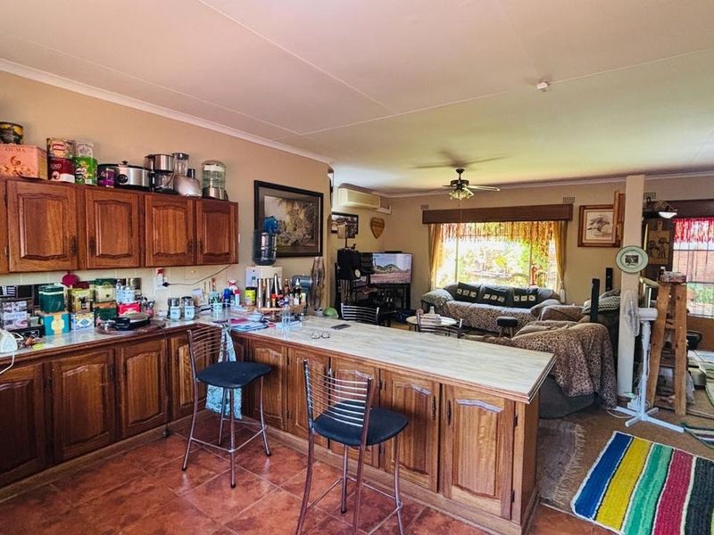 Open plan living and kitchen area featuring wooden cabinetry, a breakfast bar, tiled flooring, and direct access to the outdoor patio area.