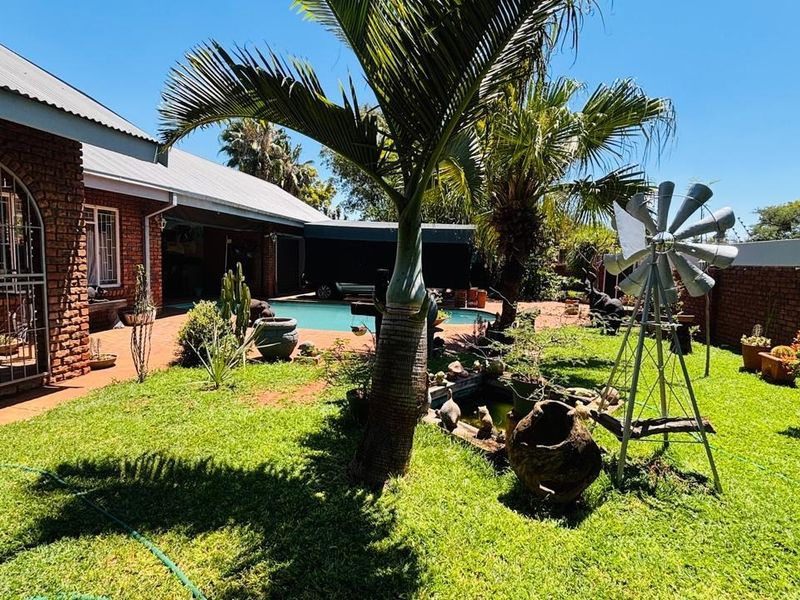 A well-maintained backyard featuring a swimming pool, lush lawn, and brick boundary walls, providing a private outdoor entertainment space.