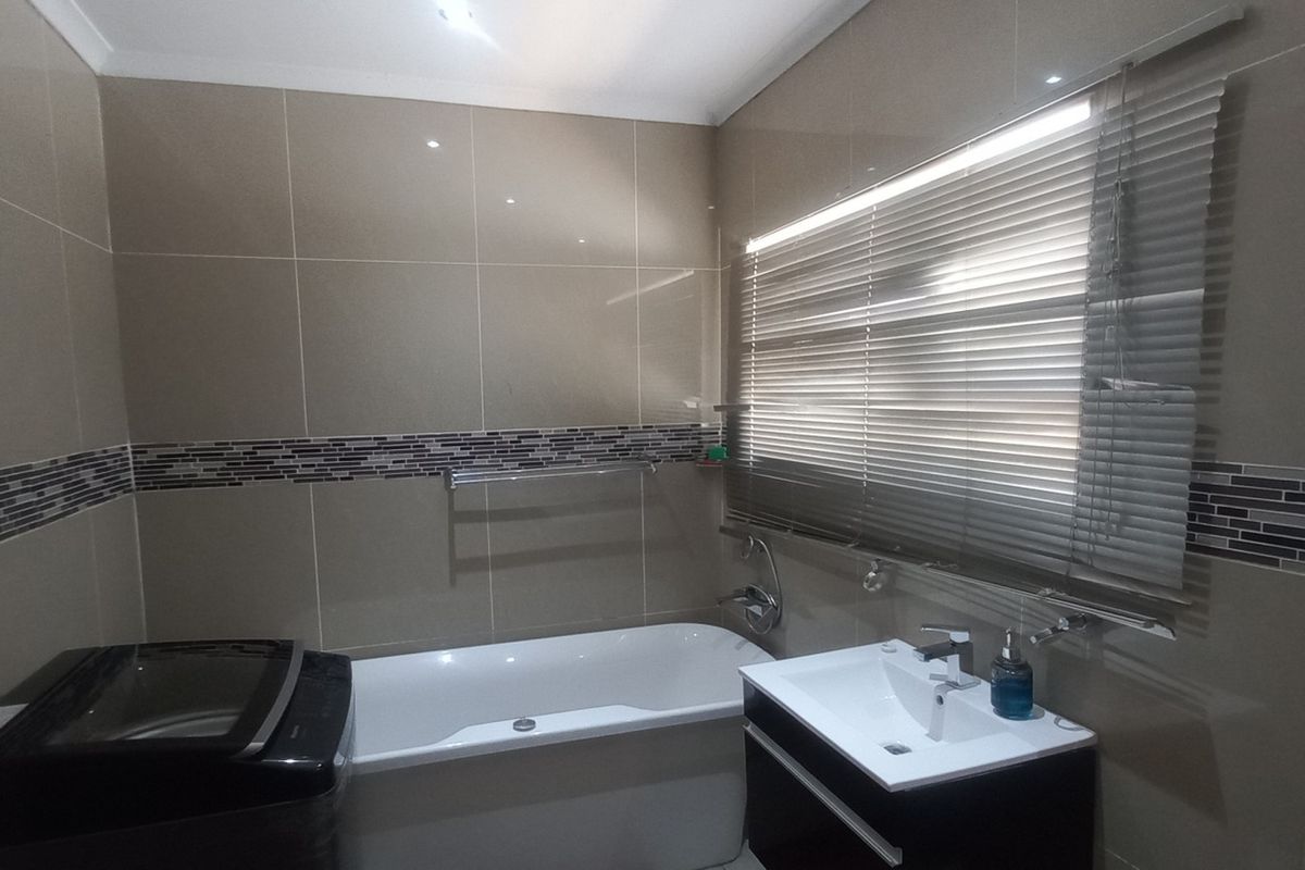 A modern bathroom featuring tiled walls, a built-in bathtub, and a sleek vanity cabinet with a basin.