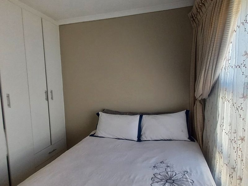 A bedroom featuring built-in cupboards and natural light from a window.