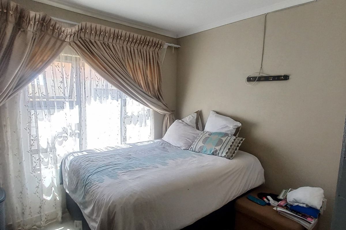 A standard bedroom featuring a large sliding glass door with curtain tracks, providing natural light and access to the exterior.