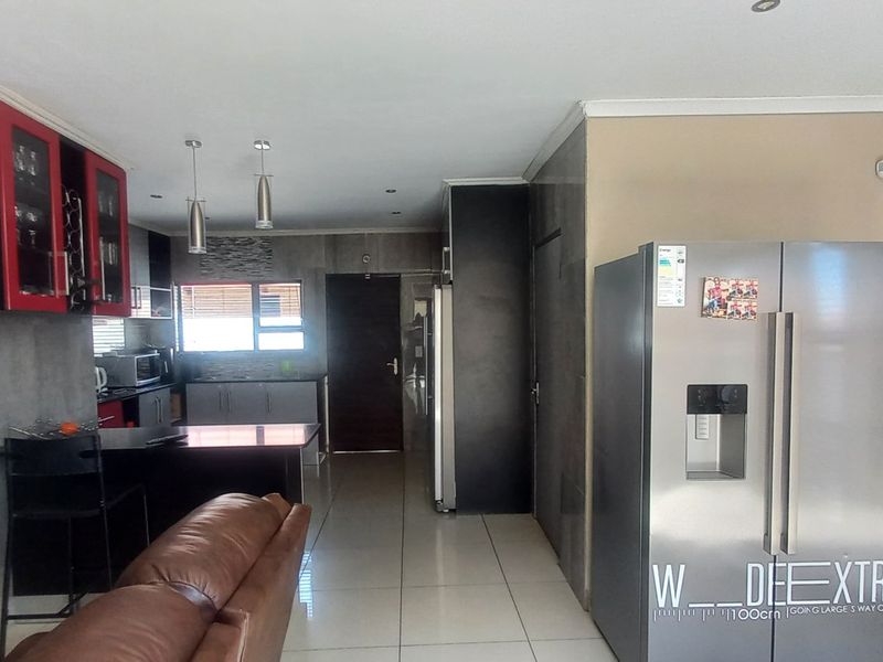 Open plan living and kitchen area featuring modern cabinetry, a central island, tiled flooring, and direct access to the exterior through a sliding glass door.