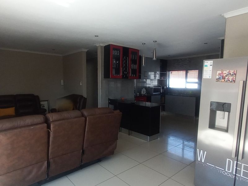 Open-plan living and kitchen area featuring tiled flooring, recessed lighting, and a functional kitchen layout with a breakfast bar.