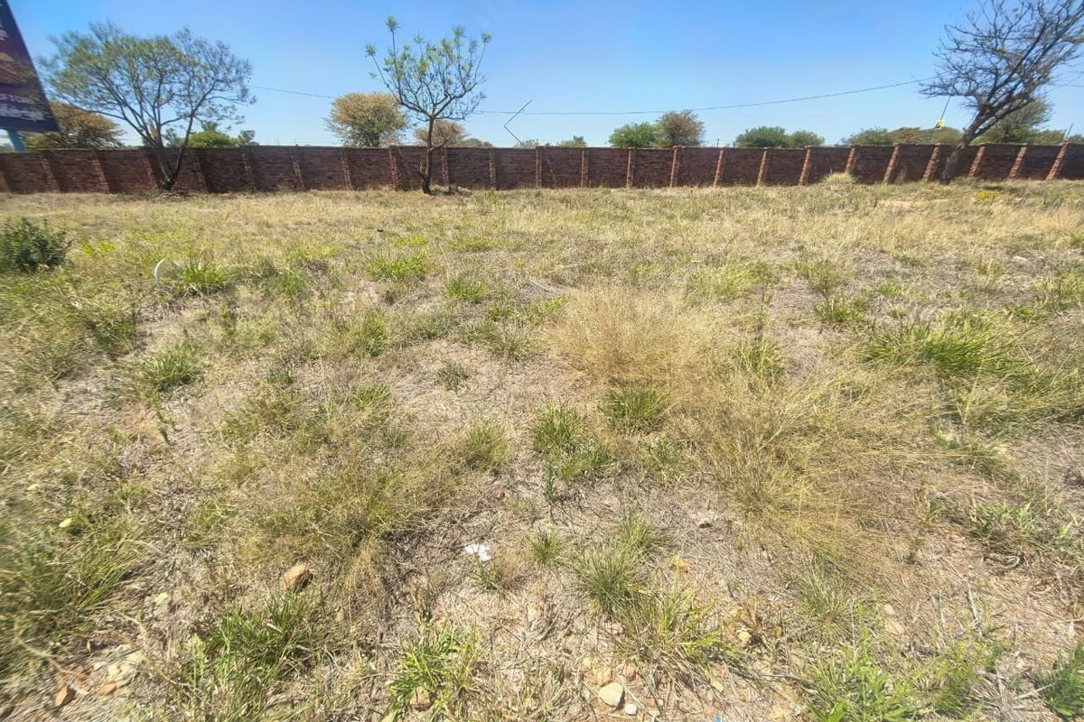 A vacant residential plot featuring natural grass coverage and a secure brick perimeter wall.
