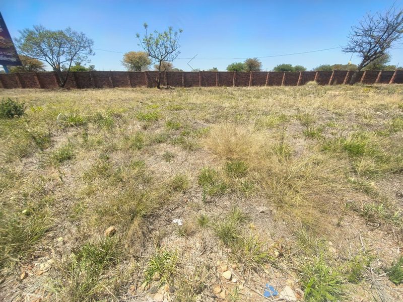 A vacant residential plot featuring natural grass coverage and a secure brick perimeter wall.