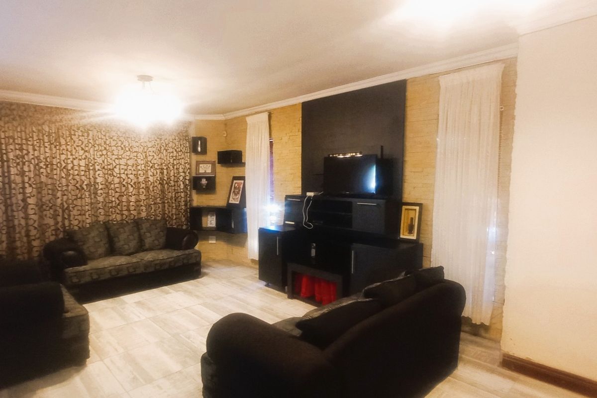 A living room featuring tiled flooring and a textured feature wall, providing a functional space for relaxation.