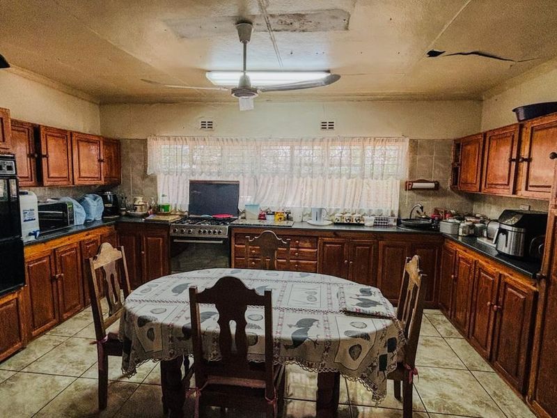 A dated kitchen featuring extensive wooden cabinetry, a built-in oven, and gas hob, requiring ceiling repairs and cosmetic updates to modernize the space.