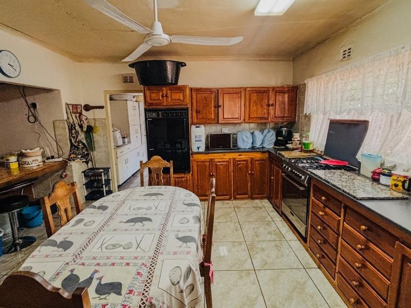A dated kitchen featuring wooden cabinetry, built-in oven, and tiled flooring, offering significant potential for modernization and renovation.