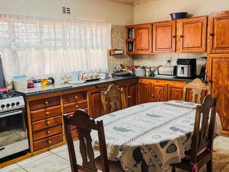 A functional kitchen featuring traditional wooden cabinetry, granite countertops, tiled flooring, and a freestanding stove, offering a classic and practical layout.