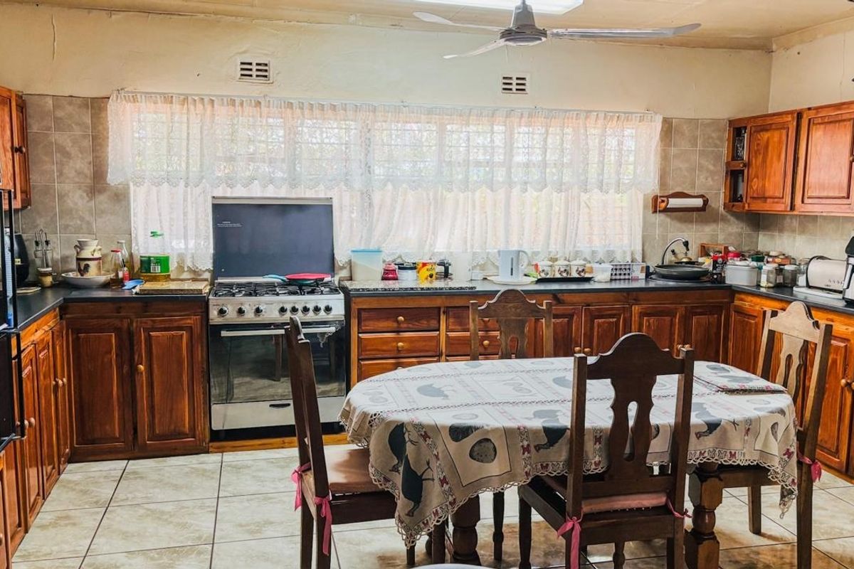 A traditional kitchen featuring extensive wooden cabinetry, a built-in oven, gas stove, and tiled flooring, offering a functional layout with classic finishes.