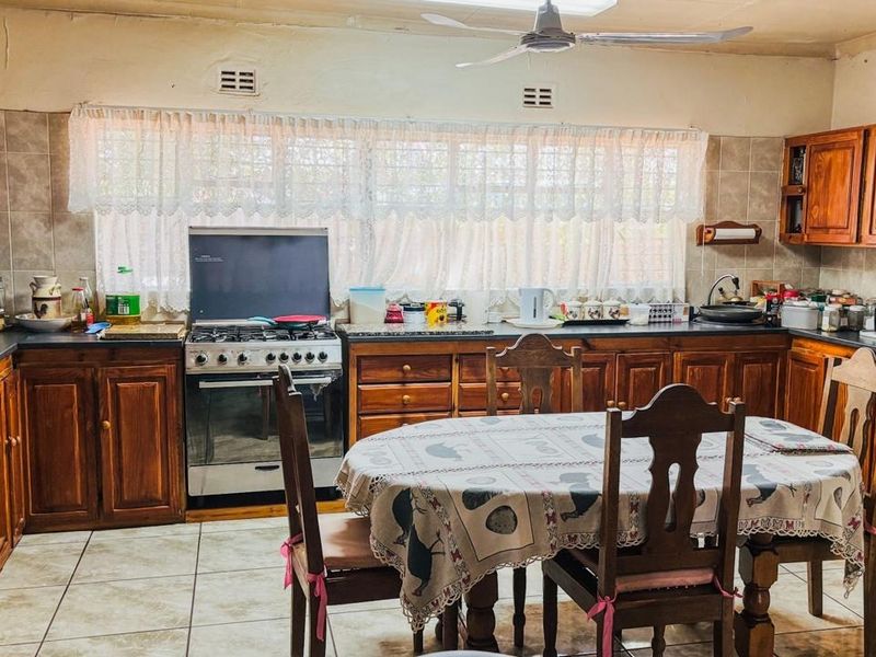 A traditional kitchen featuring extensive wooden cabinetry, a built-in oven, gas stove, and tiled flooring, offering a functional layout with classic finishes.