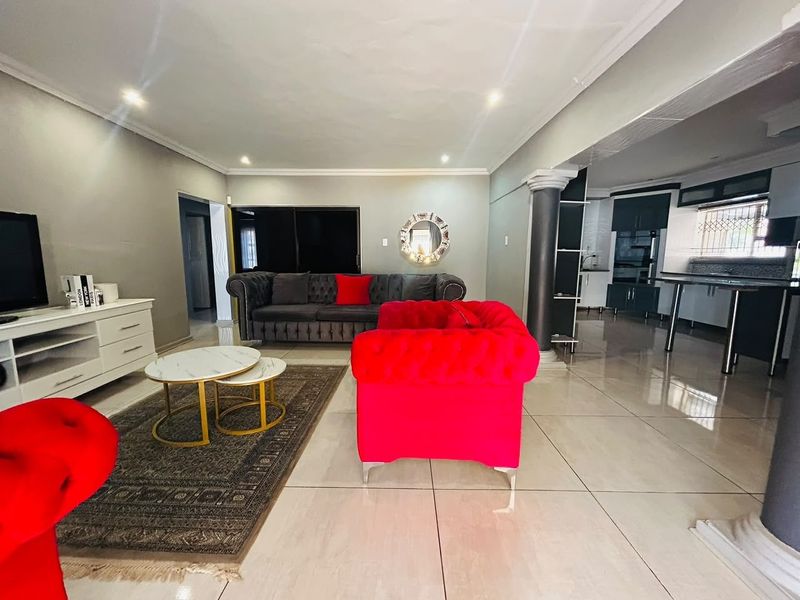 Spacious open-plan living area featuring polished porcelain floor tiles, recessed lighting, and a seamless transition into the adjacent kitchen space.