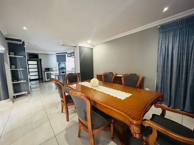 Spacious open-plan dining and kitchen area featuring polished floor tiles, modern recessed lighting, and contemporary kitchen cabinetry.